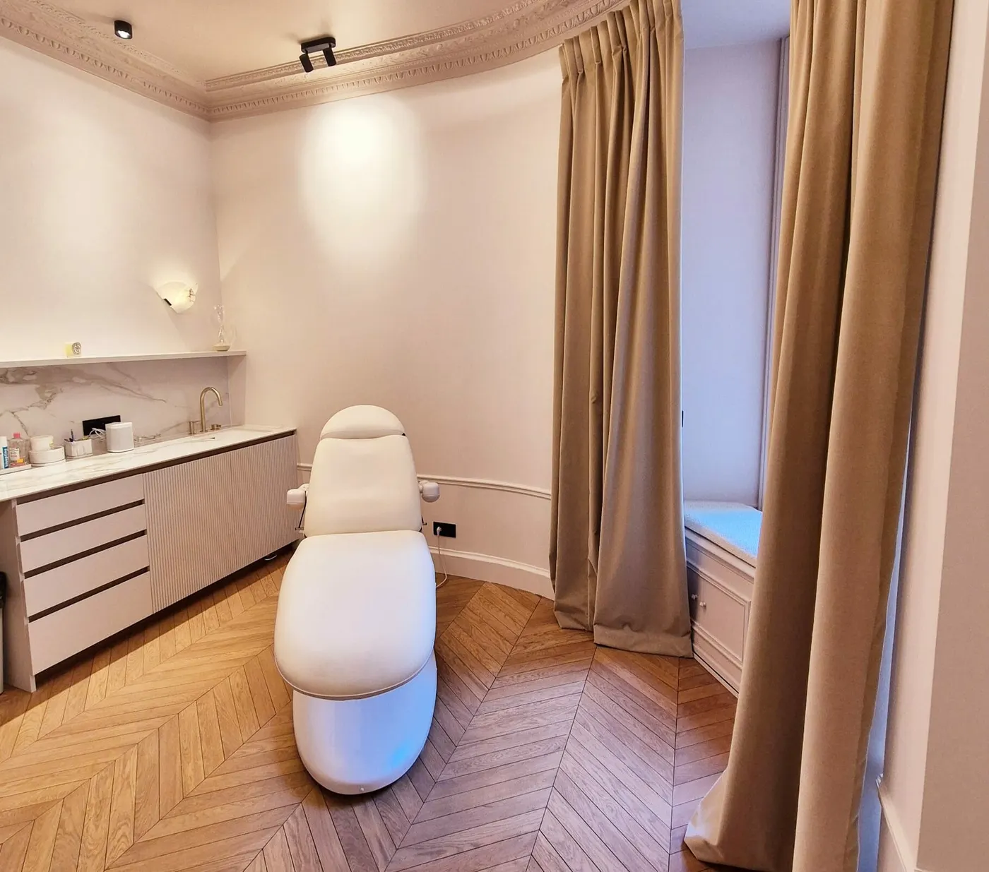 Salle de soins du cabinet : fauteuil d'examen, plan de travail en marbre, grands rideaux